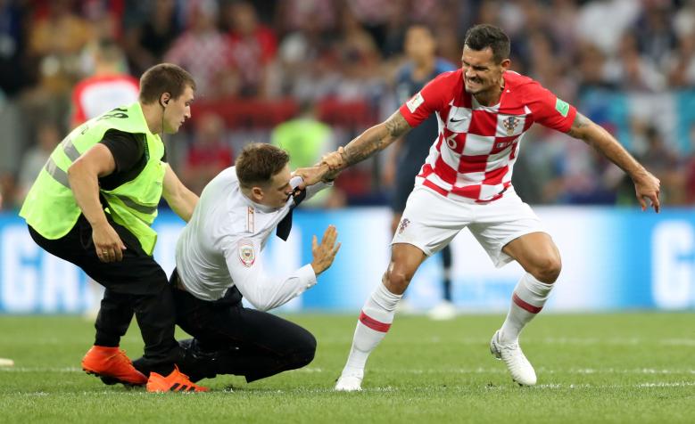 A steward apprehends a pitch invader while Croatia's Dejan Lovren looks on. REUTERS/Carl Recine